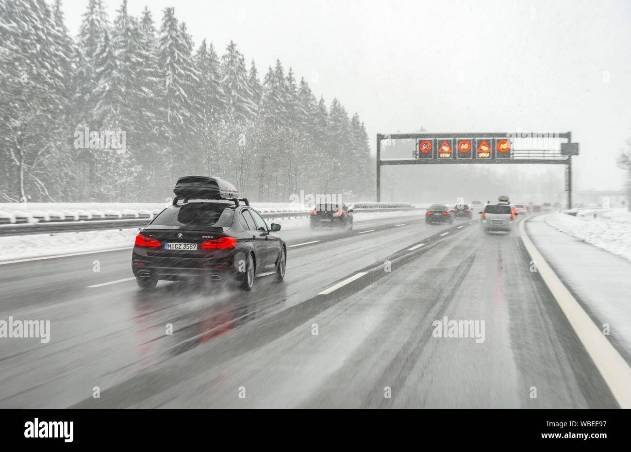 Staugefahr und Geschwindigkeitsbegrenzungen, schlechtes Wetter, Auto Verkehr während starker Schneefall und Regen auf der Autobahn A8, in der Nähe von München, Bayern, Deutschland Stockfoto