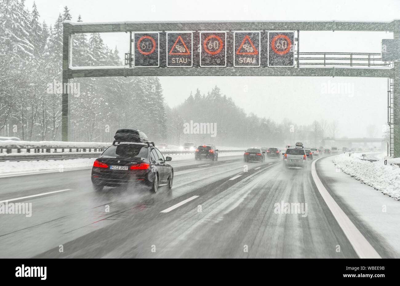 Staugefahr und Geschwindigkeitsbegrenzungen, schlechtes Wetter, Auto Verkehr während starker Schneefall und Regen auf der Autobahn A8, in der Nähe von München, Bayern, Deutschland Stockfoto