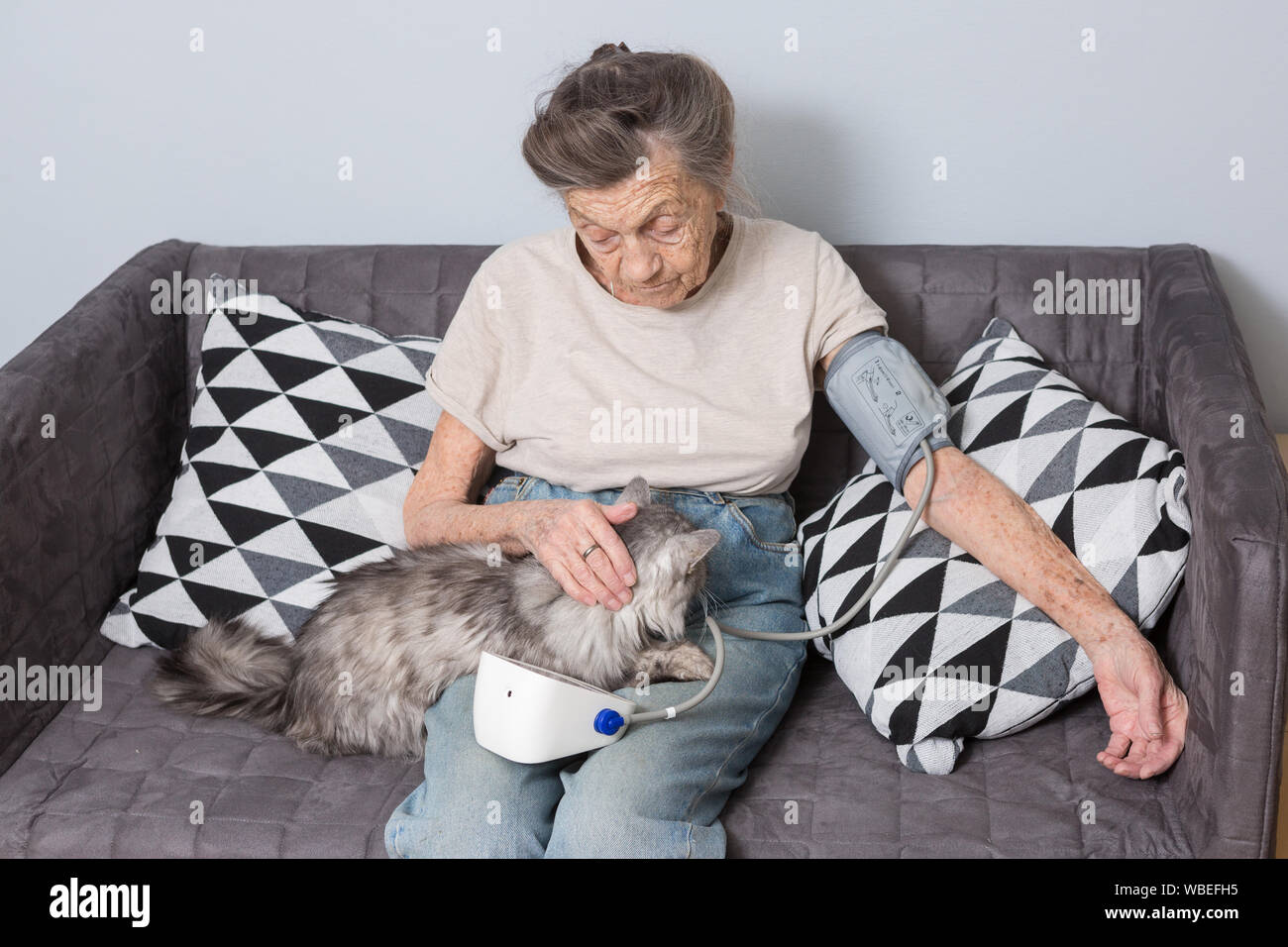 Das Thema ist sehr alte Person und gesundheitliche Probleme. Ein älterer kaukasische Frau, 90 Jahre alt, mit Falten und graue Haare, sitzt zu Hause auf dem Sofa mit Haustier Katze Stockfoto