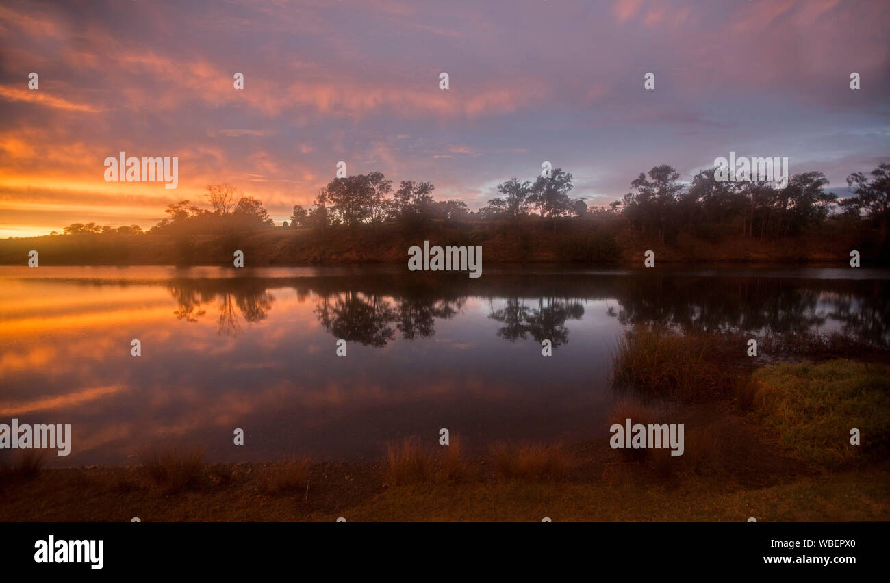Bunte sunrise auf misty morning mit Wolken und Flussufer Bäume in ruhigem Wasser von Manning River bei Wingham NSW Australien wider Stockfoto