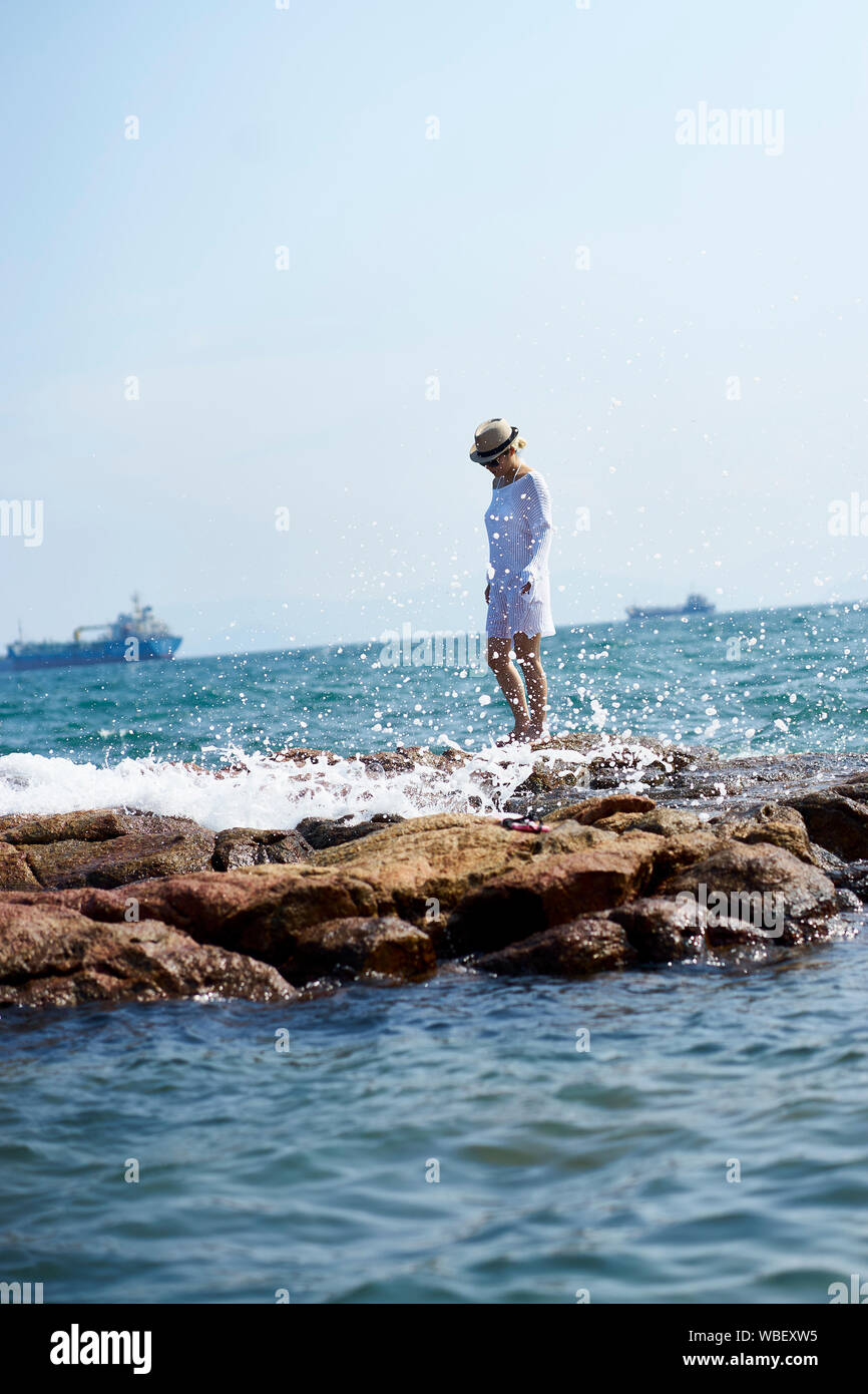 Junge asiatische Frauen gehen auf Riffe durch das Meer Stockfoto