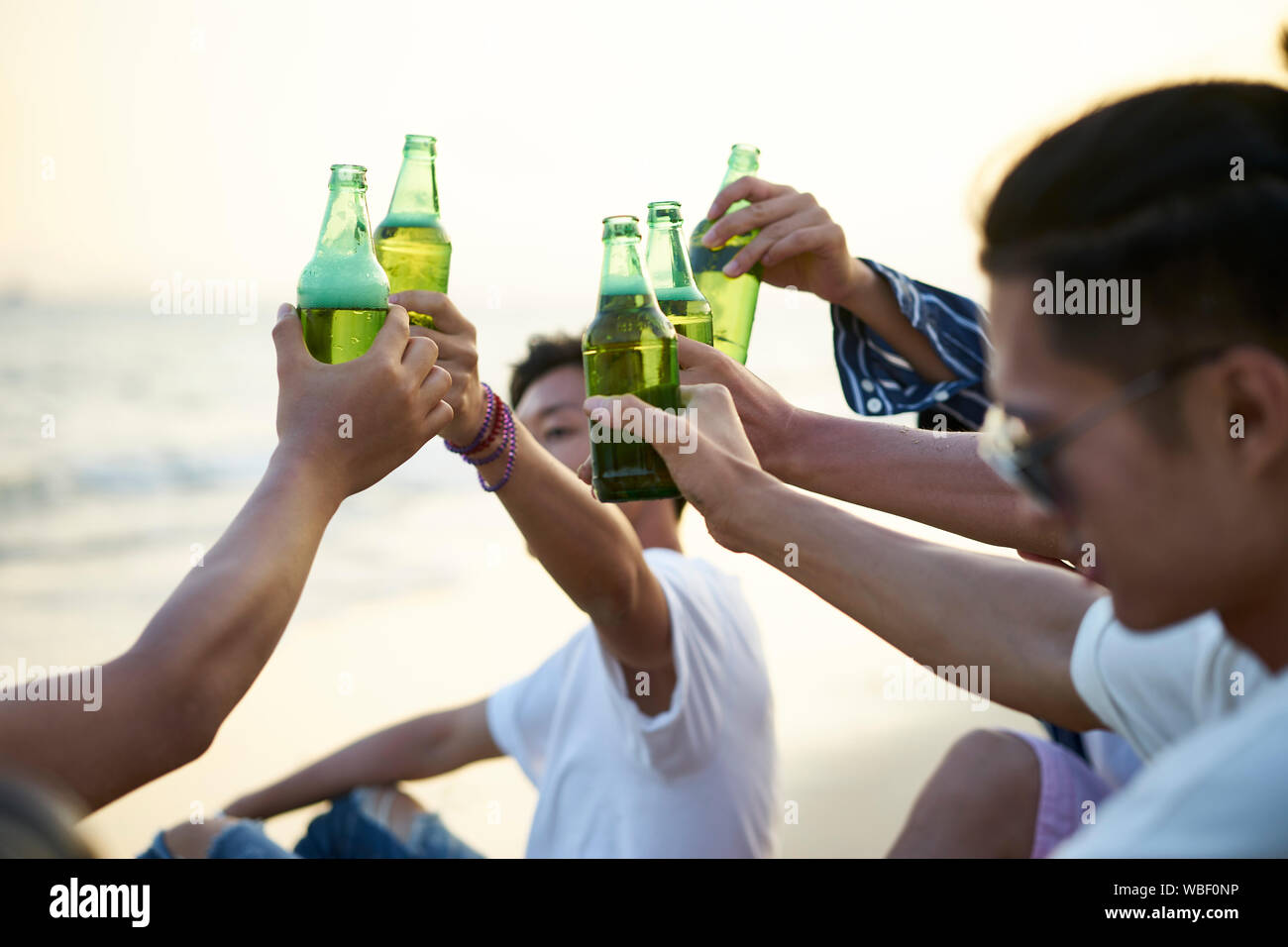 Gruppe von jungen asiatischen erwachsene Männer trinken Bier auf Flaschen toasten am Strand Stockfoto