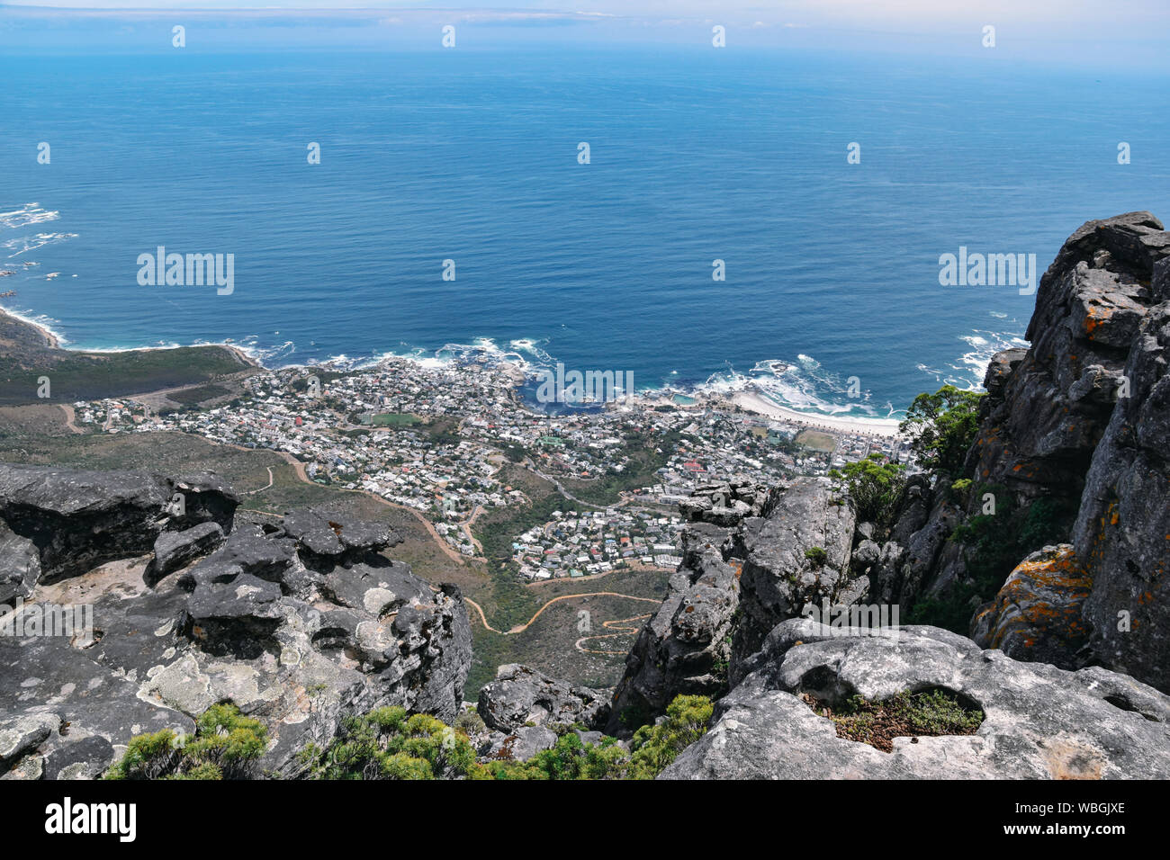 Luftaufnahme von Camps Bay und die Küste gegen den blauen Ozean vom Tafelberg in Kapstadt, Südafrika, an einem sonnigen Tag Stockfoto