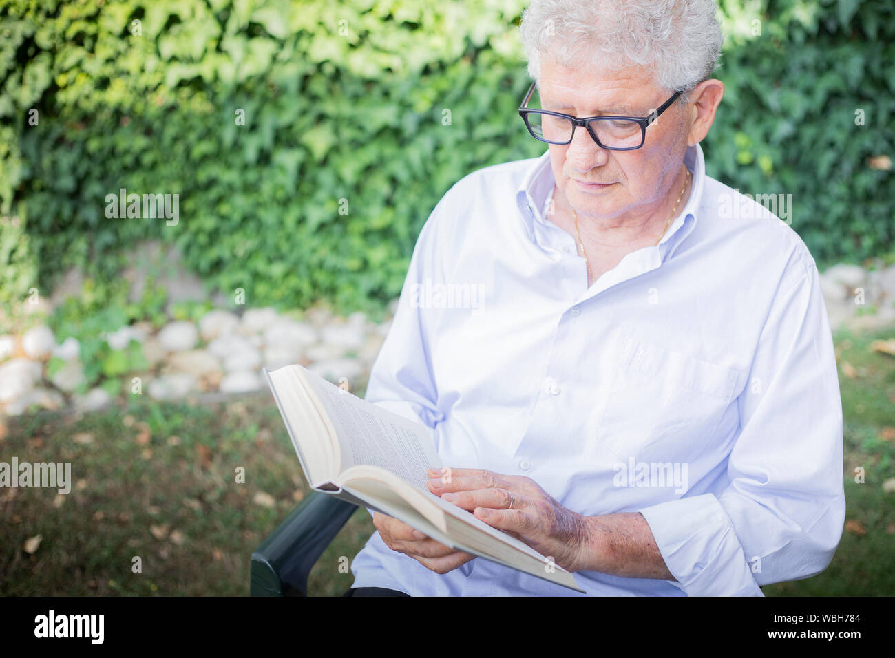 Portrait eines älteren kaukasischen Mann ein Buch lesen mit Brille im Ort im Freien. Stockfoto