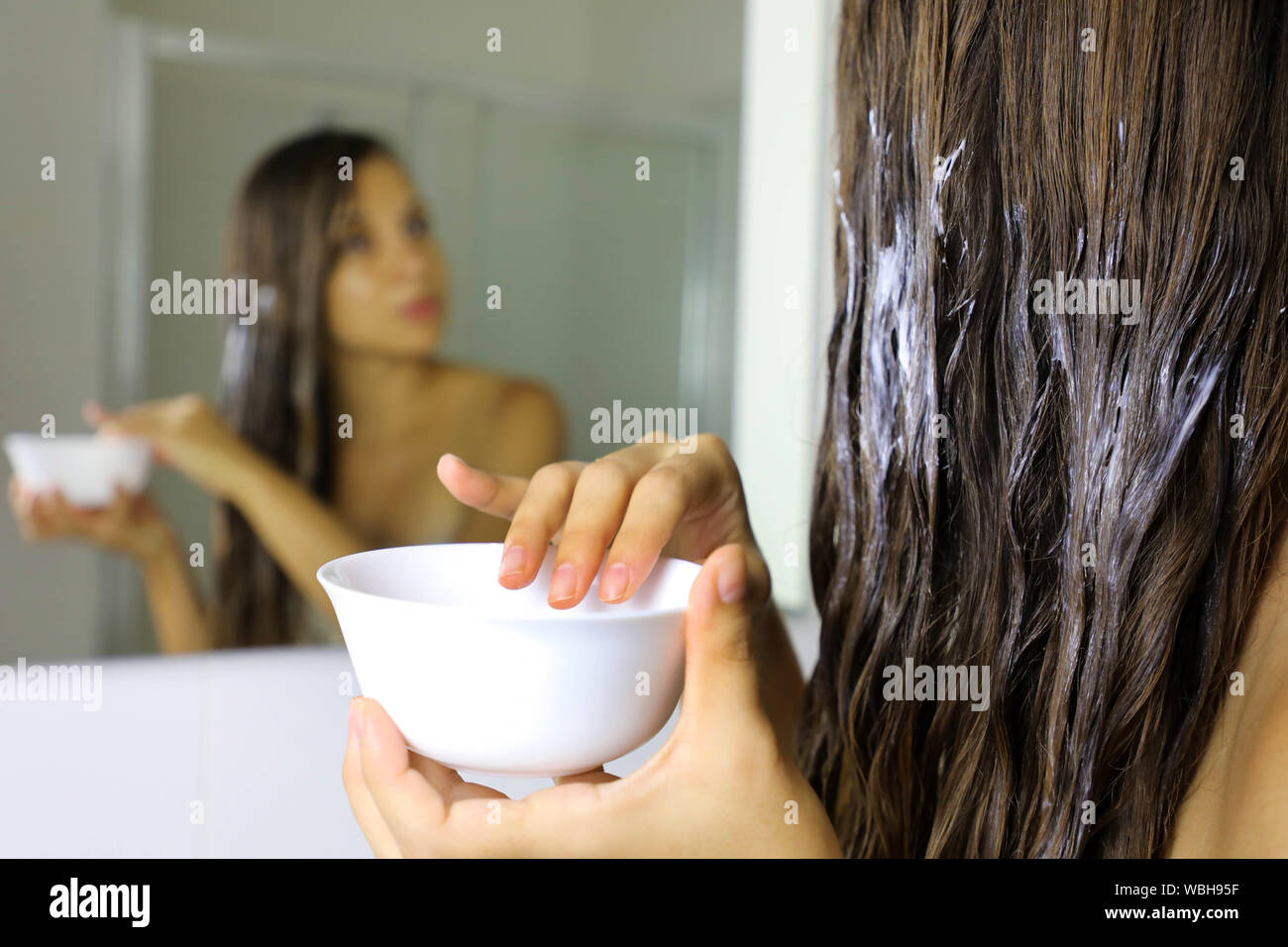 Haare maskieren. Junge Frau hand Anwendung natürliche Maske auf lange gesunde Haare. Gesundheit und Schönheit Konzept. Stockfoto