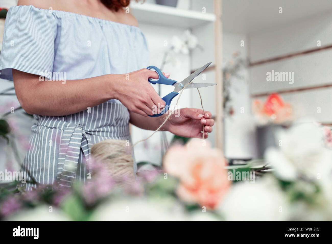 Hart arbeitenden weiblichen Blumenhändler in Hellblau Outfit schneiden Gewinde Stockfoto