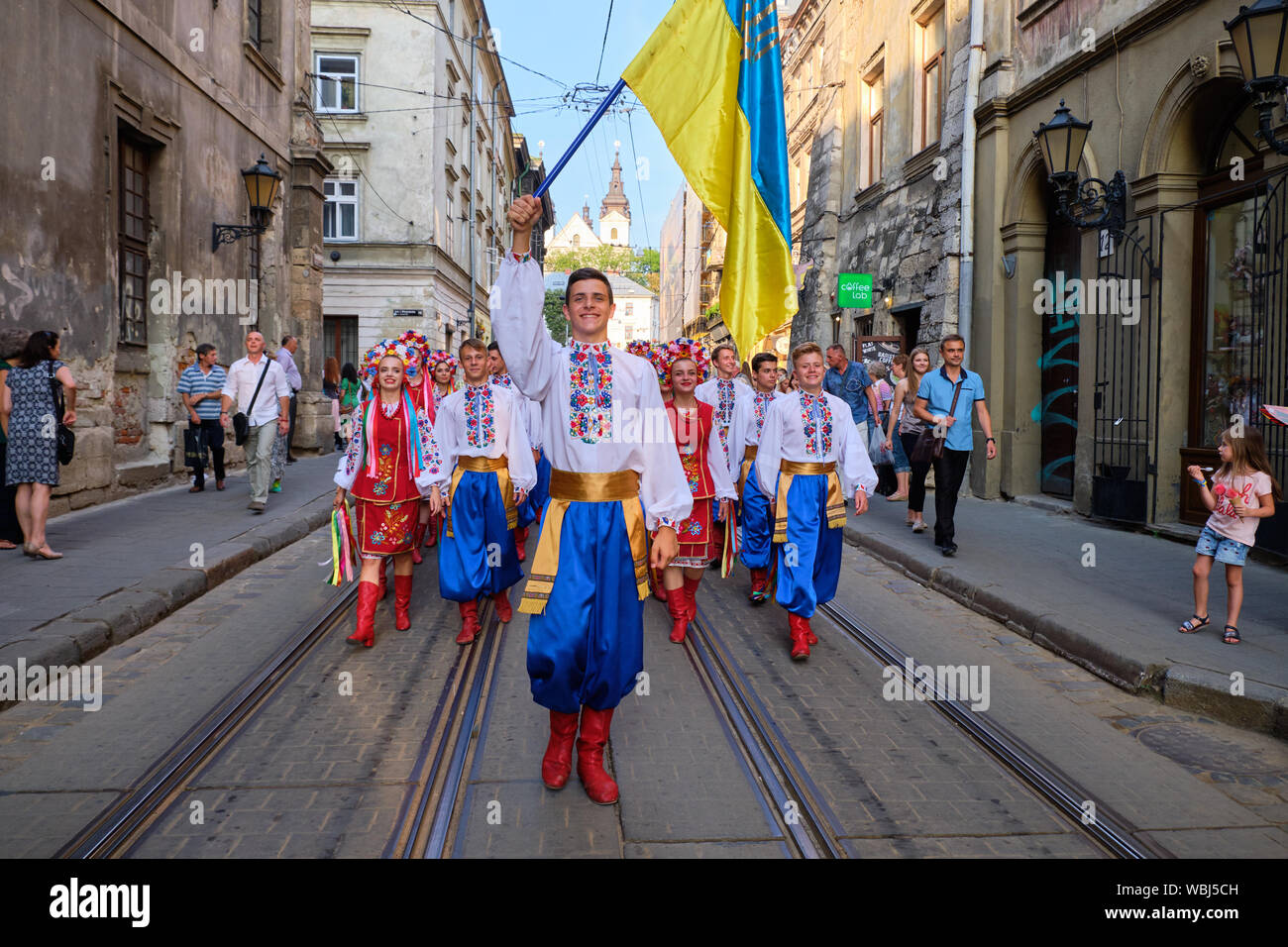 Die ukrainische Folklore Gruppe unter der Leitung von Fahnenträger zu Fuß durch die Straßen während der Parade der Etnovyr Festival in der Straße von Lviv, Ukraine Stockfoto