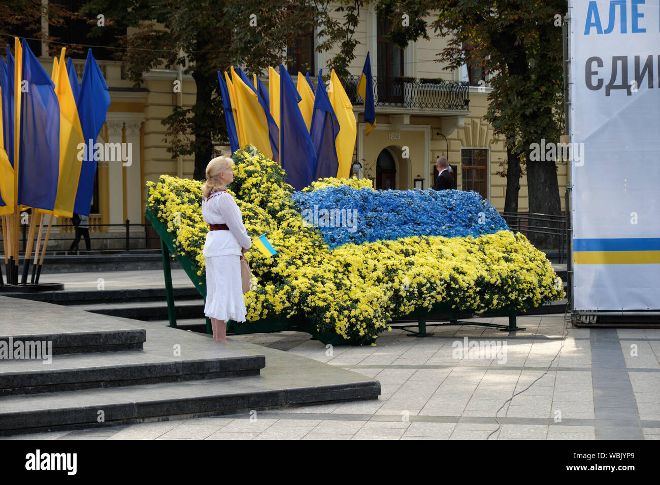 Ukrainische Frauen durch eine Flagge von Blumen während der ukrainischen Unabhängigkeit Tag Zeremonie in Lemberg, Ukraine stehend Stockfoto