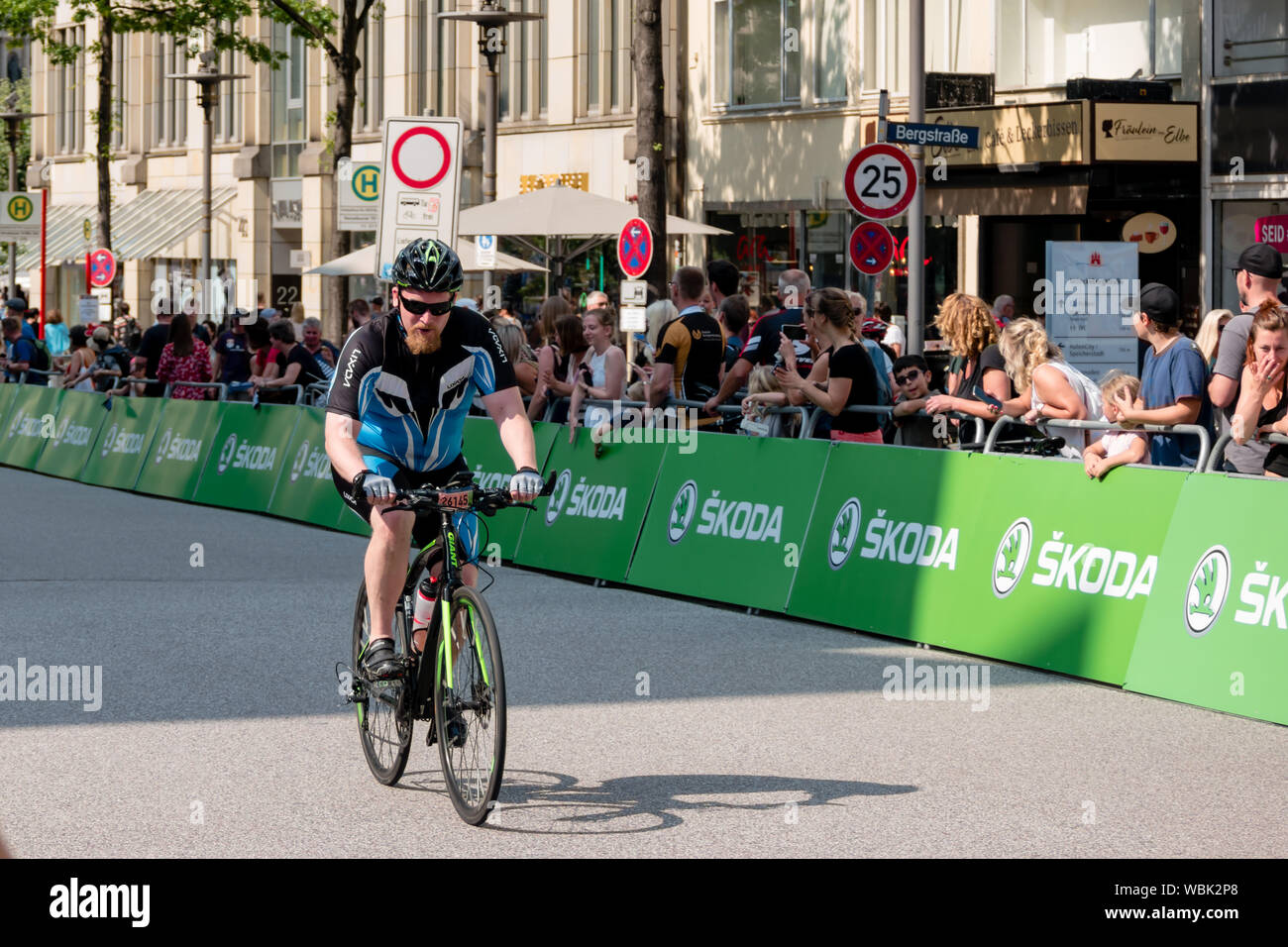 Ein Radfahrer an der 2019 Euroeyes Cyclassics radfahren Wettbewerb in Hamburg, Deutschland, beobachtet von Straße Zuschauer Stockfoto