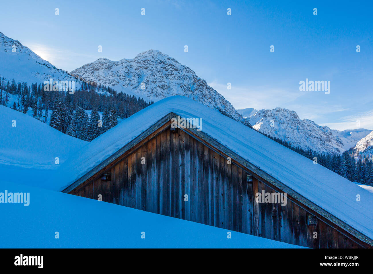 Almhütte in den Schweizer Alpen in der Nähe von Arosa im Winter mit Schnee bedeckt, blauer Himmel Stockfoto