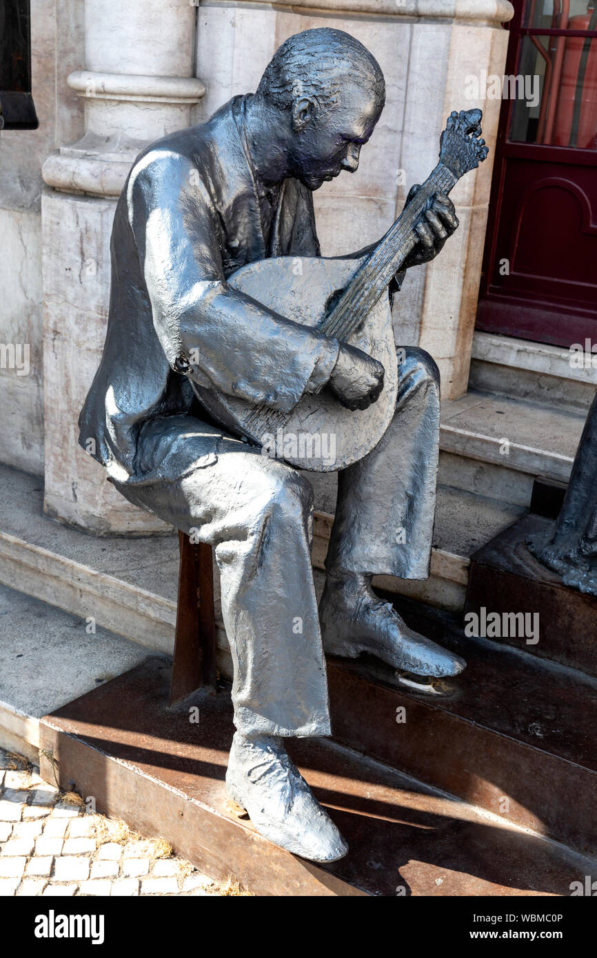 Statue eines Mannes Spielen einer portugiesischen Gitarre (Guitarra) außerhalb der Bahnhof Rossio, Lissabon, Portugal. Stockfoto