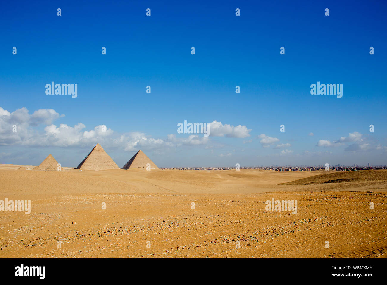 Drei Pyramiden (von rechts nach links) Khufu, Khafre und Menkuare in Ägypten am Morgen mit blauem Himmel und bewölkt, der Hintergrund ist die Stadt von Gizeh. T Stockfoto