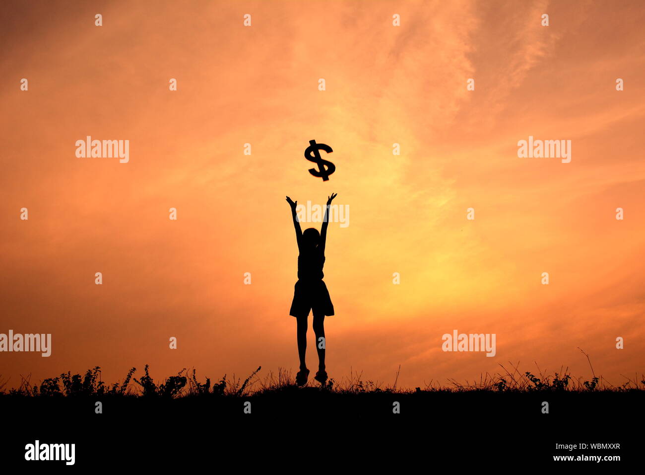 Silhouette von Mädchen werfen ein Dollarzeichen bei Sonnenuntergang Stockfoto