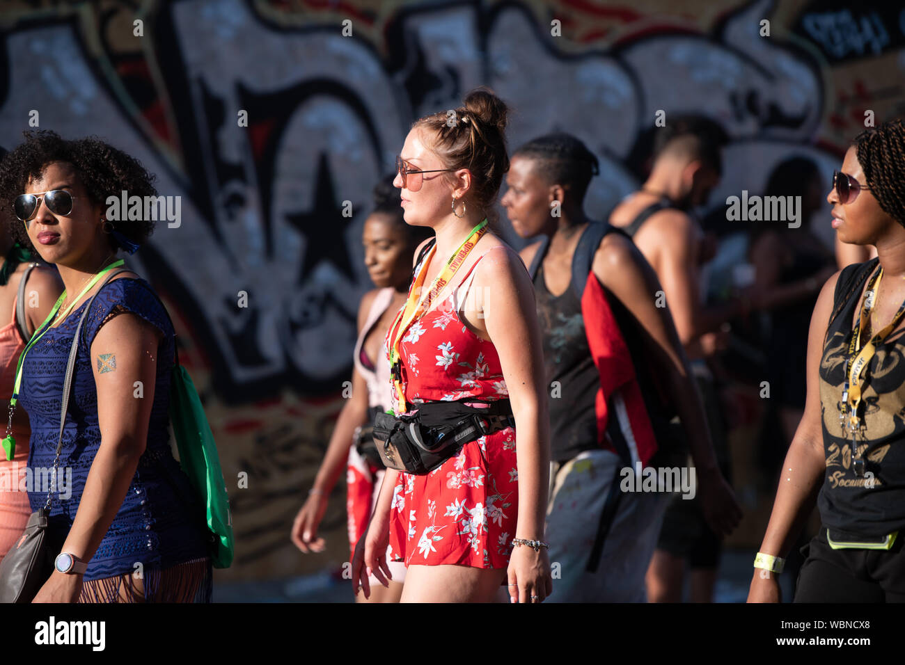 Eine Frau in Notting Hill Carnival trug ein rotes Kleid und zu Fuß in der Mitte der Straße. Stockfoto