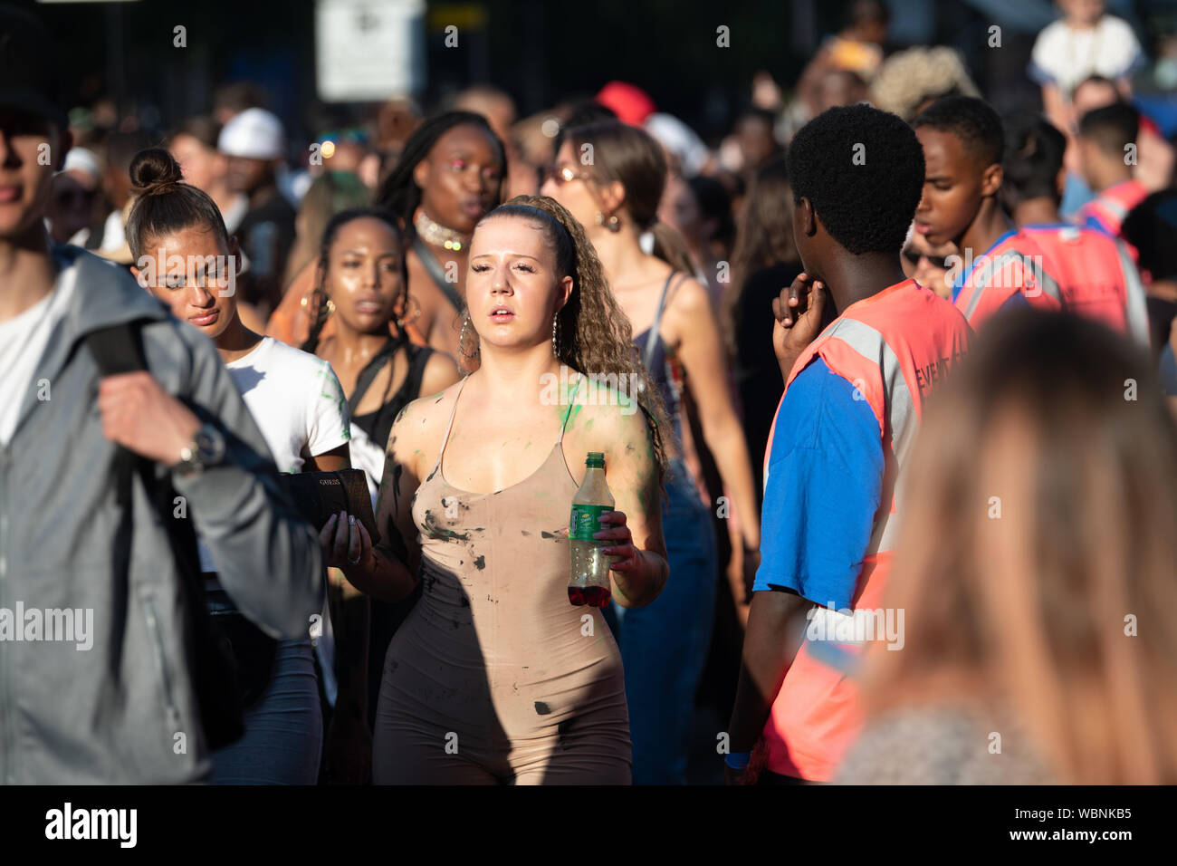 Einer weißen Frau in einer Masse an der Notting Hill Carnival eine Flasche sprite und mit Farbe bespritzt. Stockfoto