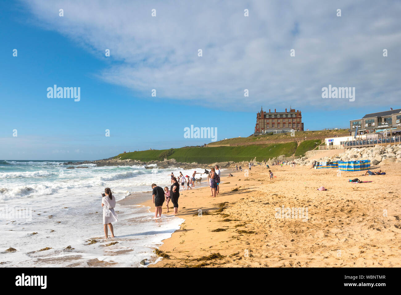 Urlauber an der Küste auf den Fistral Beach und genießen die Sonne am späten Nachmittag in Newquay in Cornwall. Stockfoto