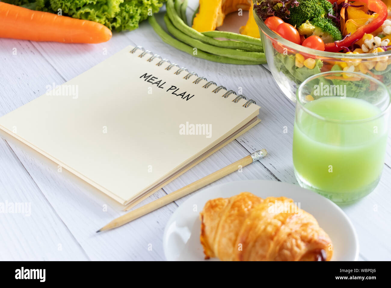 Kalorien, Speisen, Ernährung und Gewichtsabnahme Konzept. Speisen schreiben auf Notebook Planner mit Salat, Obst, Saft, Brot und Gemüse. Stockfoto