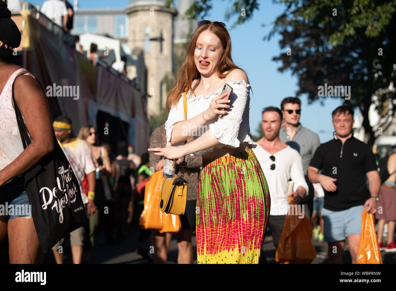 Eine weiße Frau klemmt ihre Jungen aus und Tanzen in bunten Garnituren in Notting Hill Carnival. Stockfoto