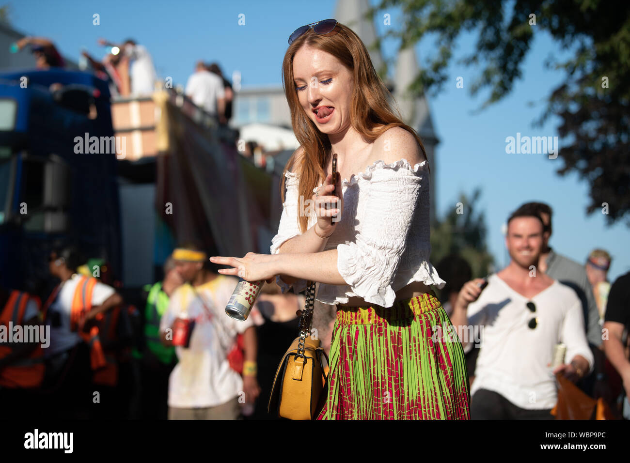Eine weiße Frau klemmt ihre Jungen aus und Tanzen in bunten Garnituren in Notting Hill Carnival. Stockfoto
