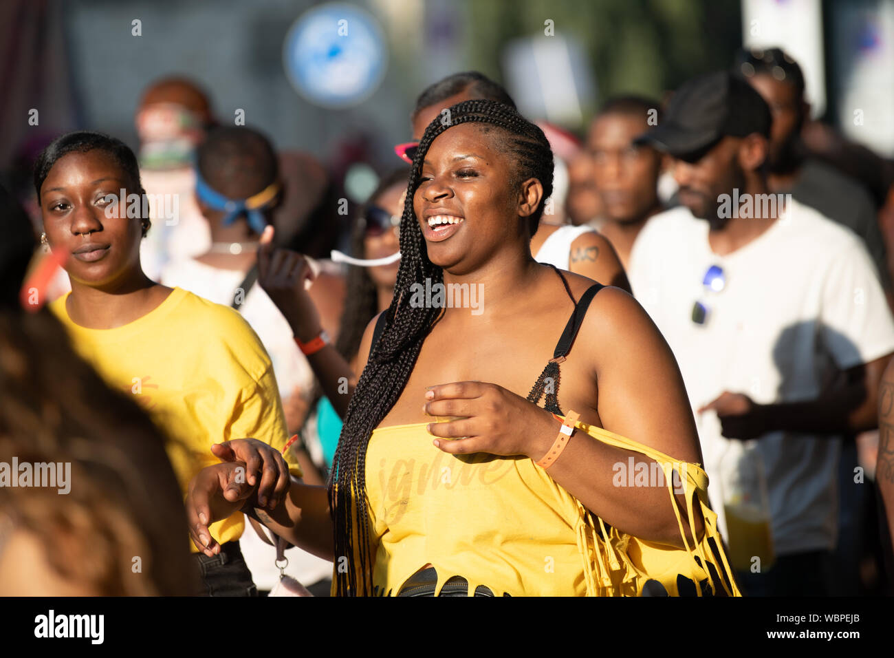 Eine schwarze Frau lächelnd und in Gelb am Notting Hill Carnival gekleidet. Stockfoto