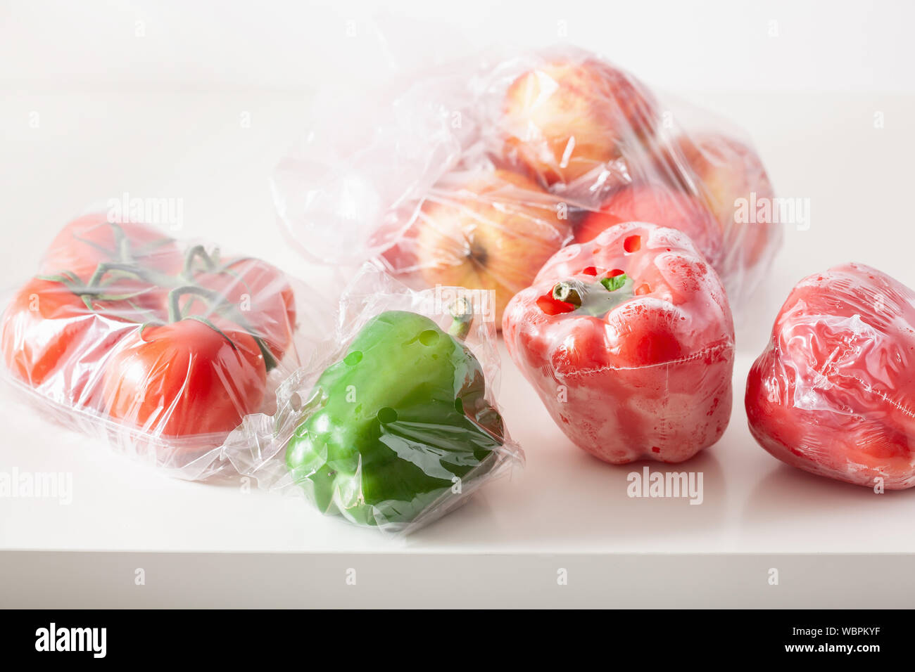 Single use Kunststoffverpackungen. Peperoni Tomaten äpfel Gemüse in Plastiktüten Stockfoto
