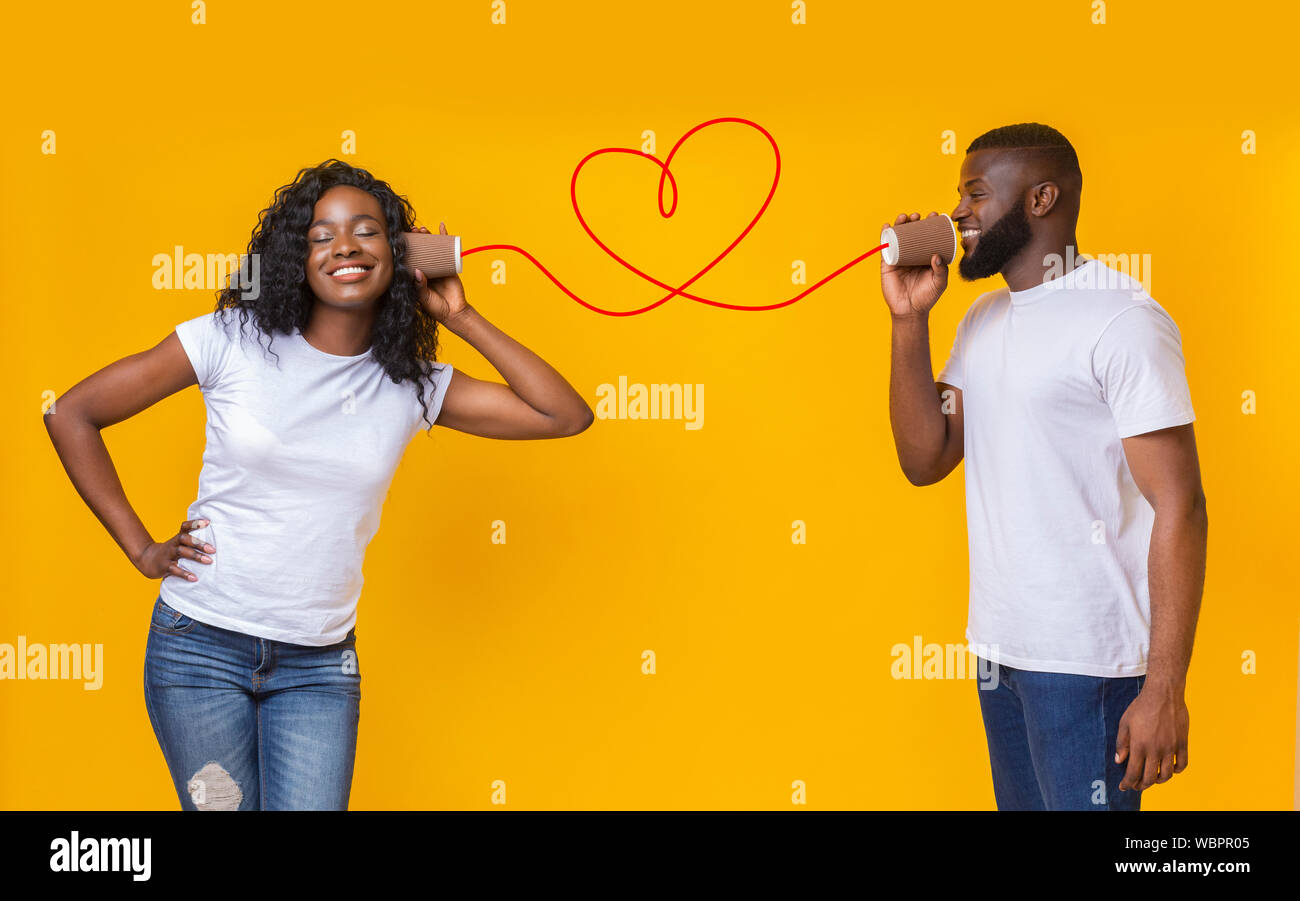Junge schwarze Paar mit können Telefon auf gelbem Hintergrund Stockfoto