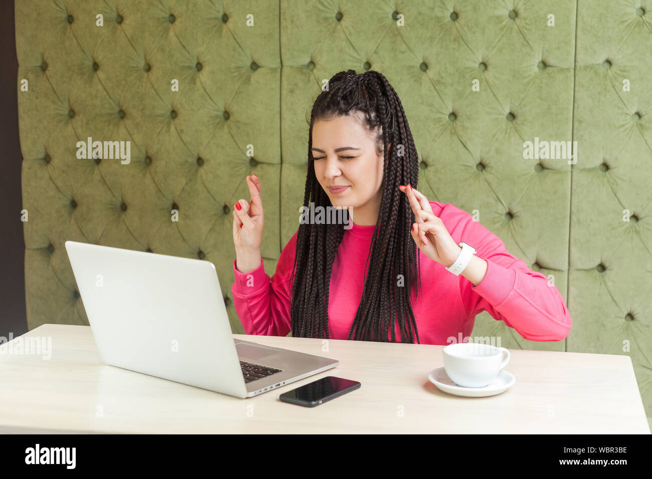 Portrait von Wunschdenken attraktive junge Arbeitnehmer Frau Freiberufler mit schwarzen dreadlocks Frisur in rosa Bluse Sitzen, Arbeiten am Laptop, geschlossenen Augen ein Stockfoto
