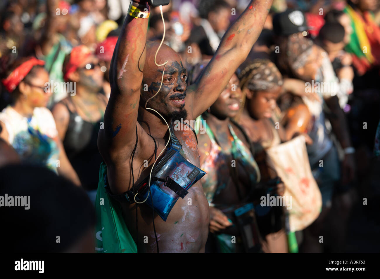 Ein schwarzer Mann, der Spaziergang durch Notting Hill Carnival abgedeckt in der Farbe. Stockfoto