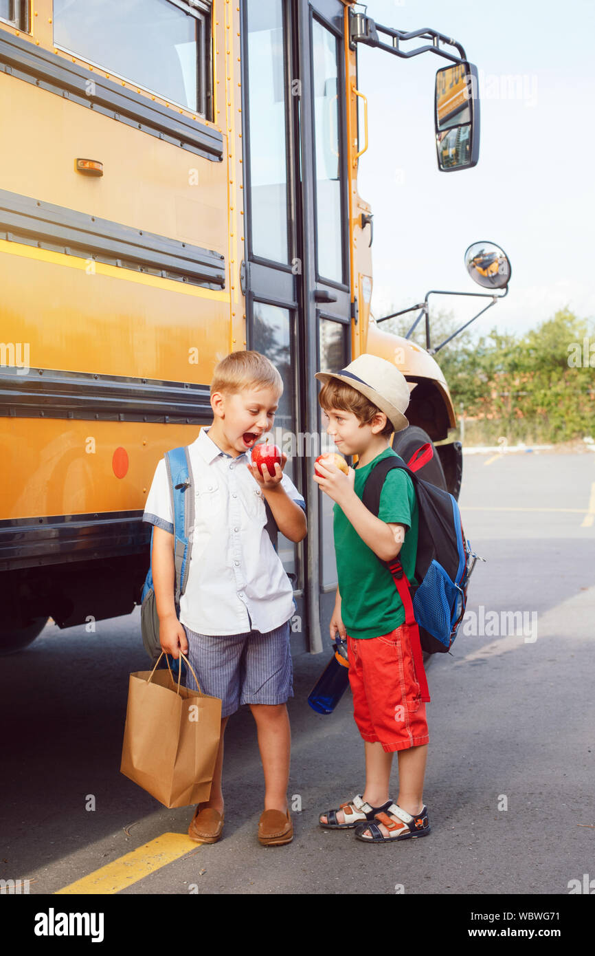 Zwei lustige glücklich Kaukasischen jungen Schüler Kinder Äpfel in der Nähe von Yellow Bus am 1. September. Bildung und zurück in die Schule. Kinder Schüler r Stockfoto