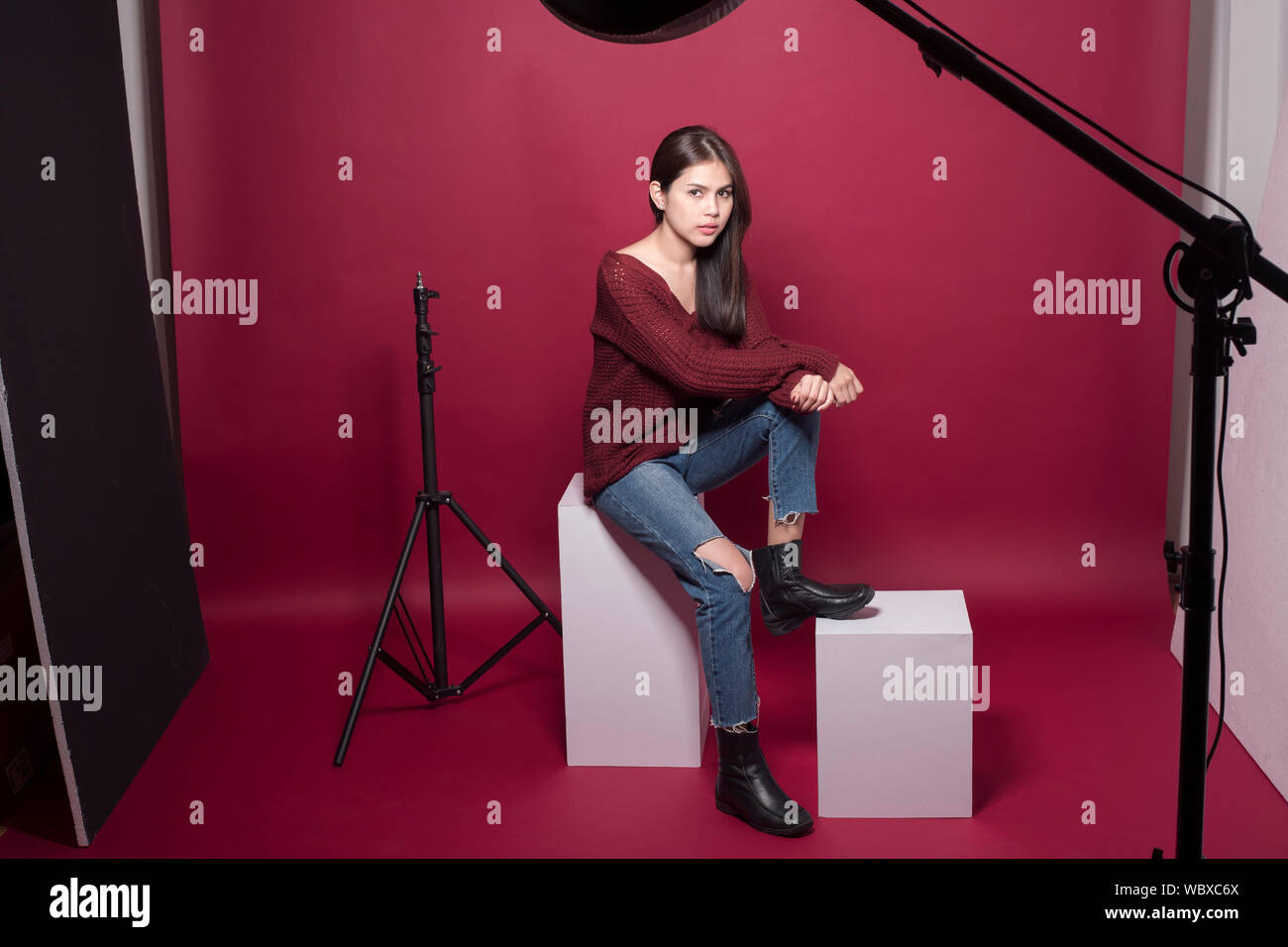 Portrait von Frau mit Stativ Kamera und Beleuchtung Sitzen im Studio Stockfoto