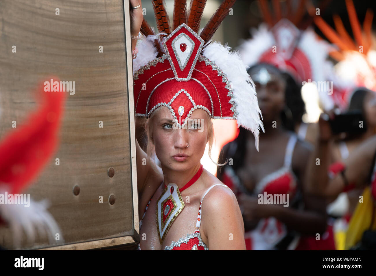 Performerin gekleidet in bunten Federn am Notting Hill Carnival, größte Karneval in Europa. Stockfoto