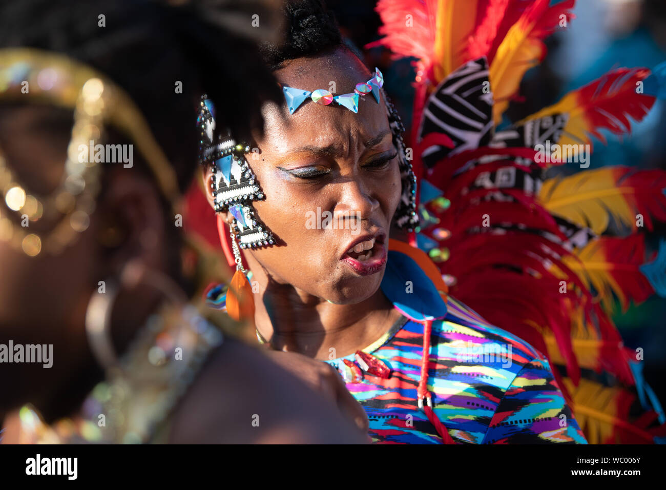 Performerin gekleidet in bunten Federn am Notting Hill Carnival, größte Karneval in Europa. Stockfoto