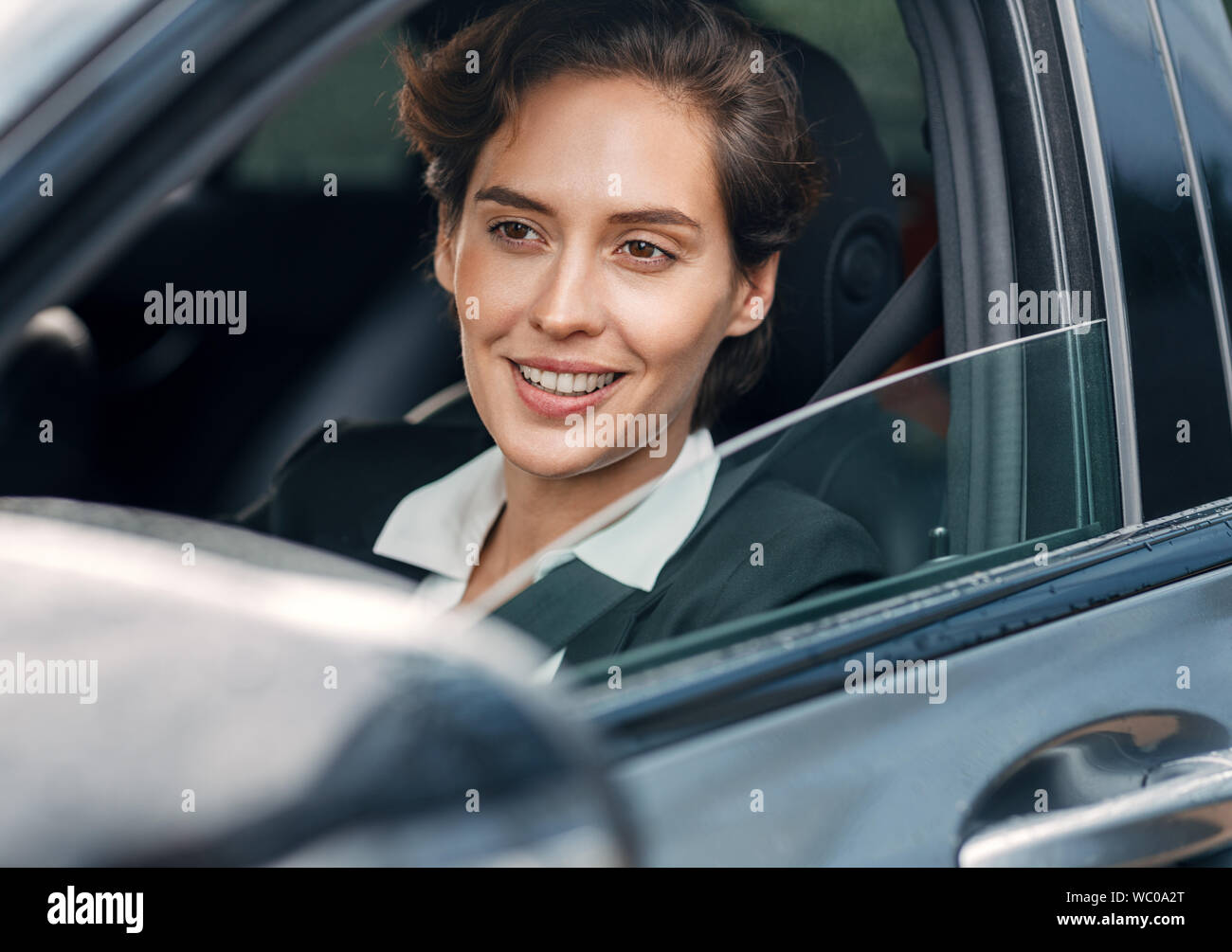 Lächelnd Geschäftsfrau in einem Auto. Junge Frauen, die in förmlichen tragen Auto fahren. Stockfoto