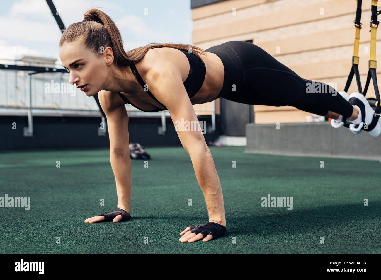 Fitness Frau tun Push-ups im Freien mit Aufhängung Bänder Stockfoto