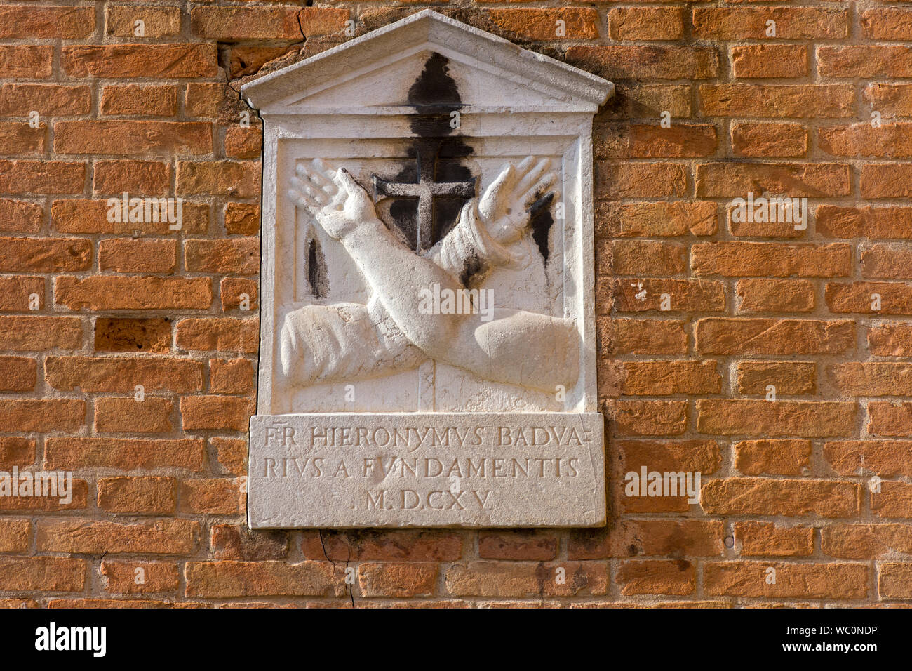Stein Reliefplatte zeigt eine gekreuzte Hände, die an der Wand durch den Rio dei San Girolamo Kanal auf der Fondamenta delle Cappuzzine, Venedig, Italien Stockfoto