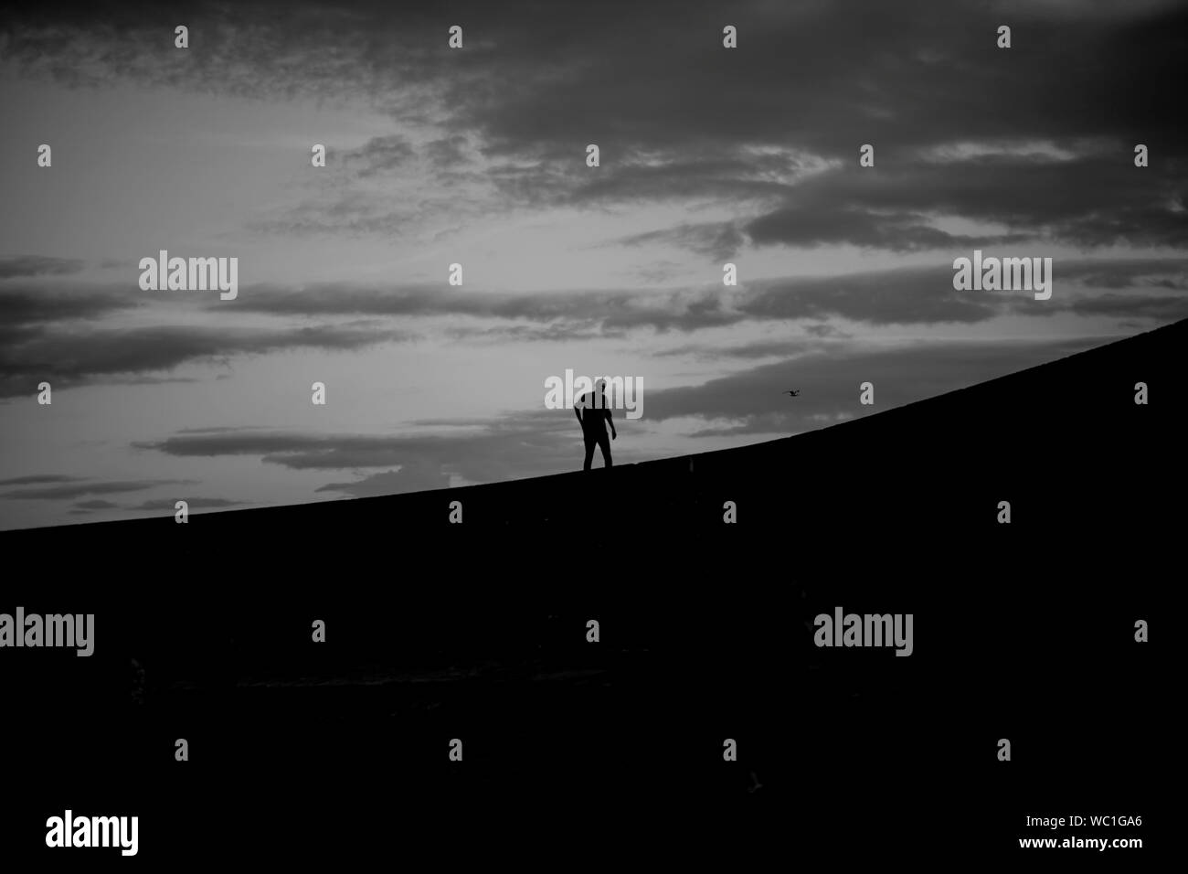 Silhouette Abbildung zu Fuß auf einem Ziegelstein pier gegen eine bewölkte Himmel Stockfoto