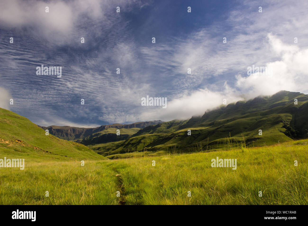 Am frühen Morgen zu Beginn der Wanderung, mit verschiedenen Arten von Wolken in verschiedenen Höhen, über die Berge, in die drakensberge fotografiert. Stockfoto