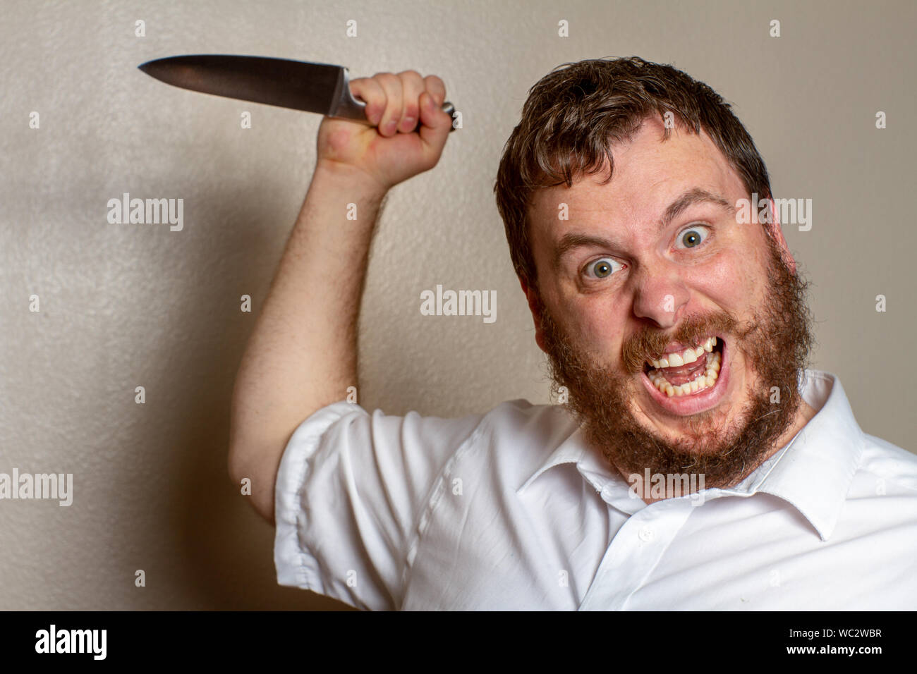 Verrückter Kerl mit einem Messer, der sich zum Angriff bereit macht Stockfoto