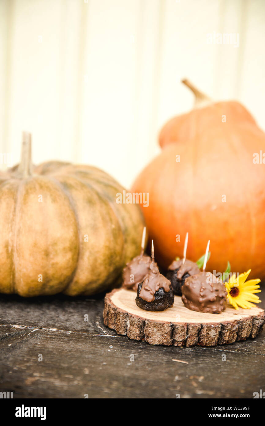 Selektiver Fokus auf handgefertigte Pralinen mit orangefarbenen Kürbisse auf dem Hintergrund im Herbst. Stockfoto