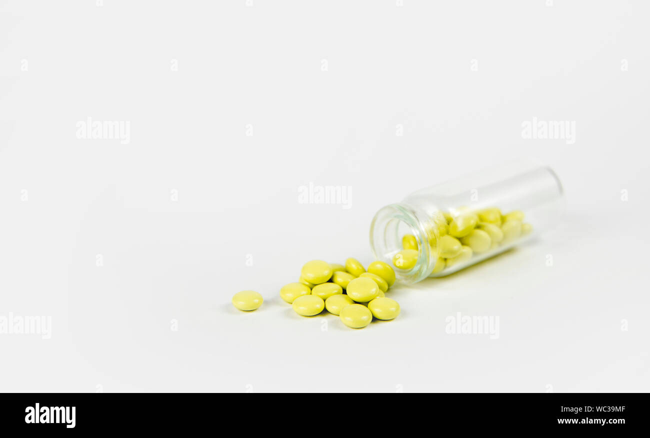 Kleines Glas Glas Flasche fiel und kleinen gelben Baldrian Pillen sind verschüttet, grauen Hintergrund. Pharmazeutische Konzept. Stockfoto