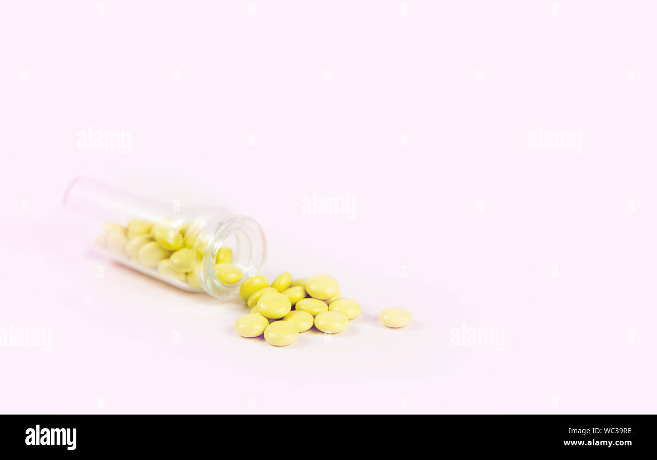 Kleines Glas Glas Flasche fiel und kleinen gelben Baldrian Pillen sind verschüttet, grauen Hintergrund. Pharmazeutische Konzept. Stockfoto