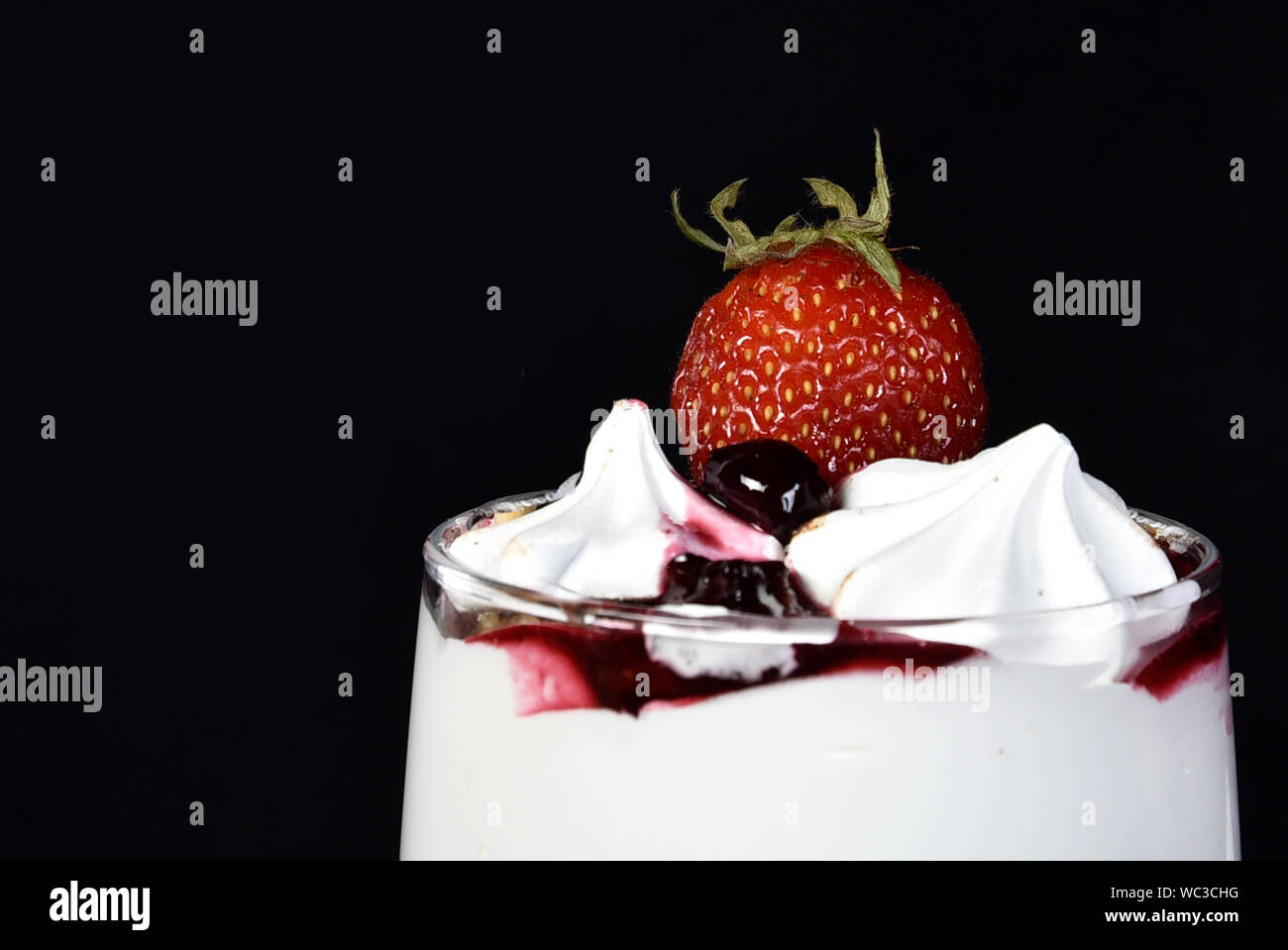 Süße nachspeise Eis in der Schüssel mit Erdbeeren Obst auf schwarzem Hintergrund. Stockfoto