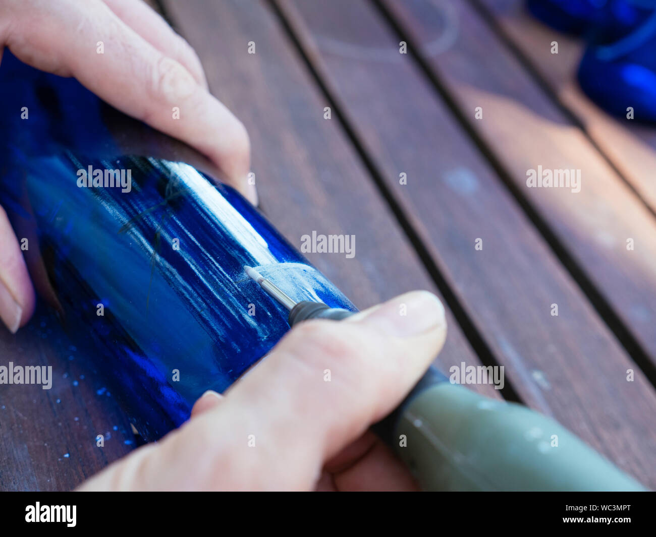 Mann Gravur eine Zahl in einer blauen Flasche es als Plot in einem Gemüsegarten zu verwenden. Stockfoto