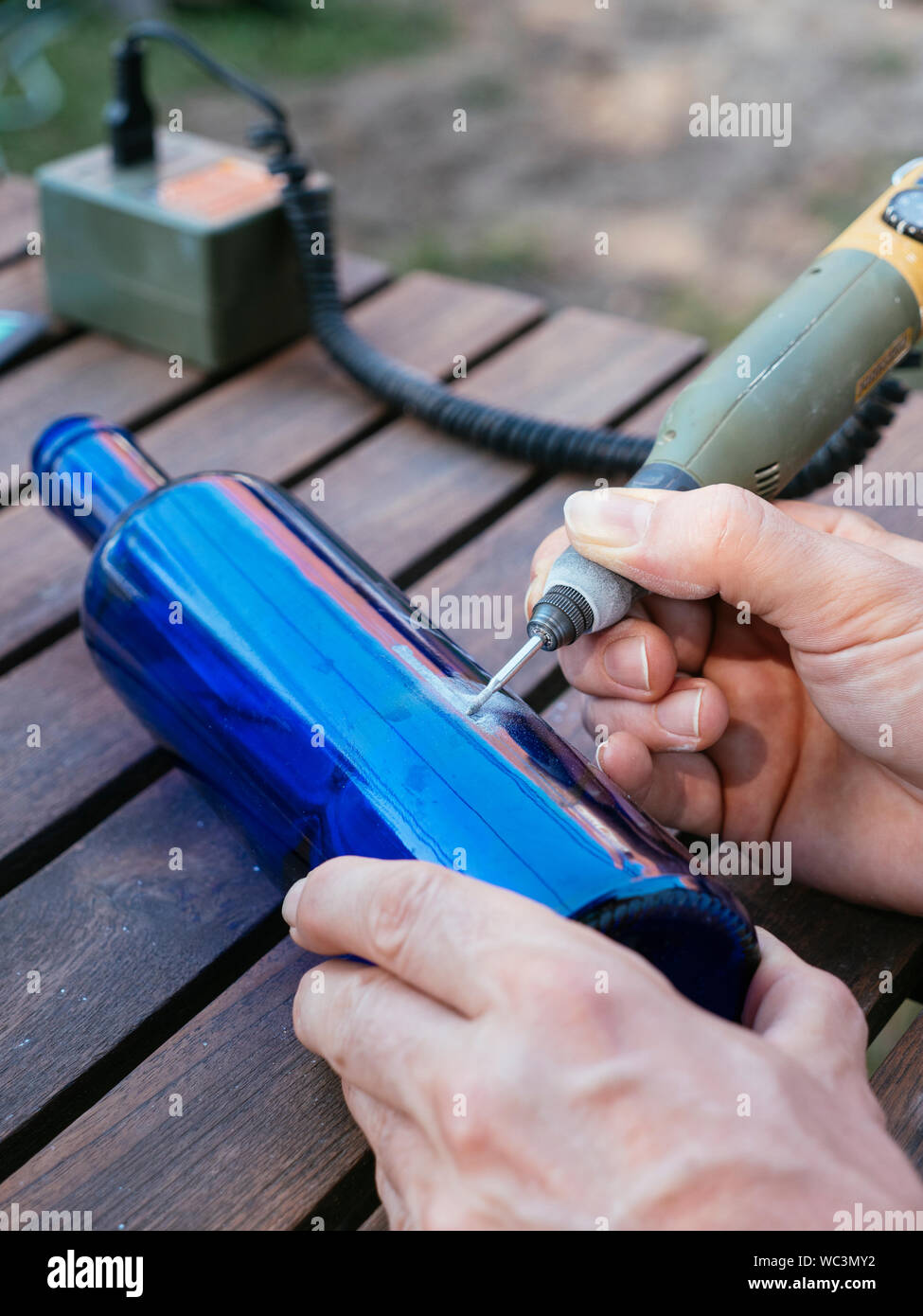 Mann Gravur eine Zahl in einer blauen Flasche es als Plot in einem Gemüsegarten zu verwenden. Stockfoto