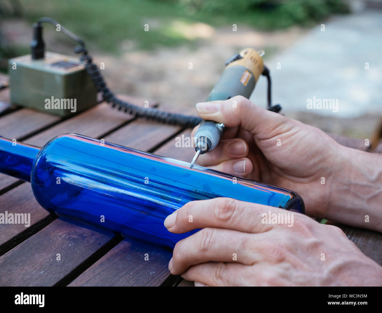 Mann Gravur eine Zahl in einer blauen Flasche es als Plot in einem Gemüsegarten zu verwenden. Stockfoto