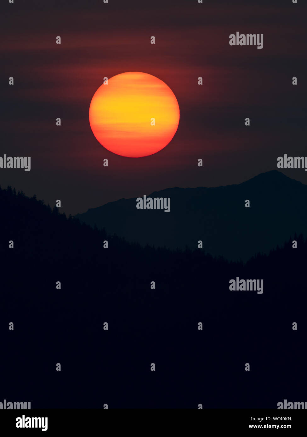 Der Sonnenuntergang über der Insel Chichagof im Südosten Alaskas, USA, machte durch Rauch aus Wildbränden lebendiger Stockfoto