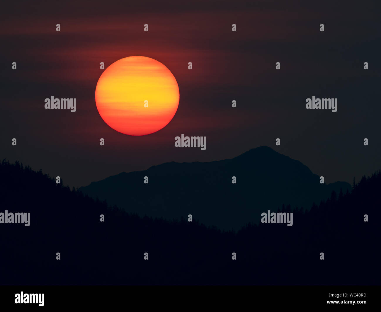 Der Sonnenuntergang über der Insel Chichagof im Südosten Alaskas, USA, machte durch Rauch aus Wildbränden lebendiger Stockfoto