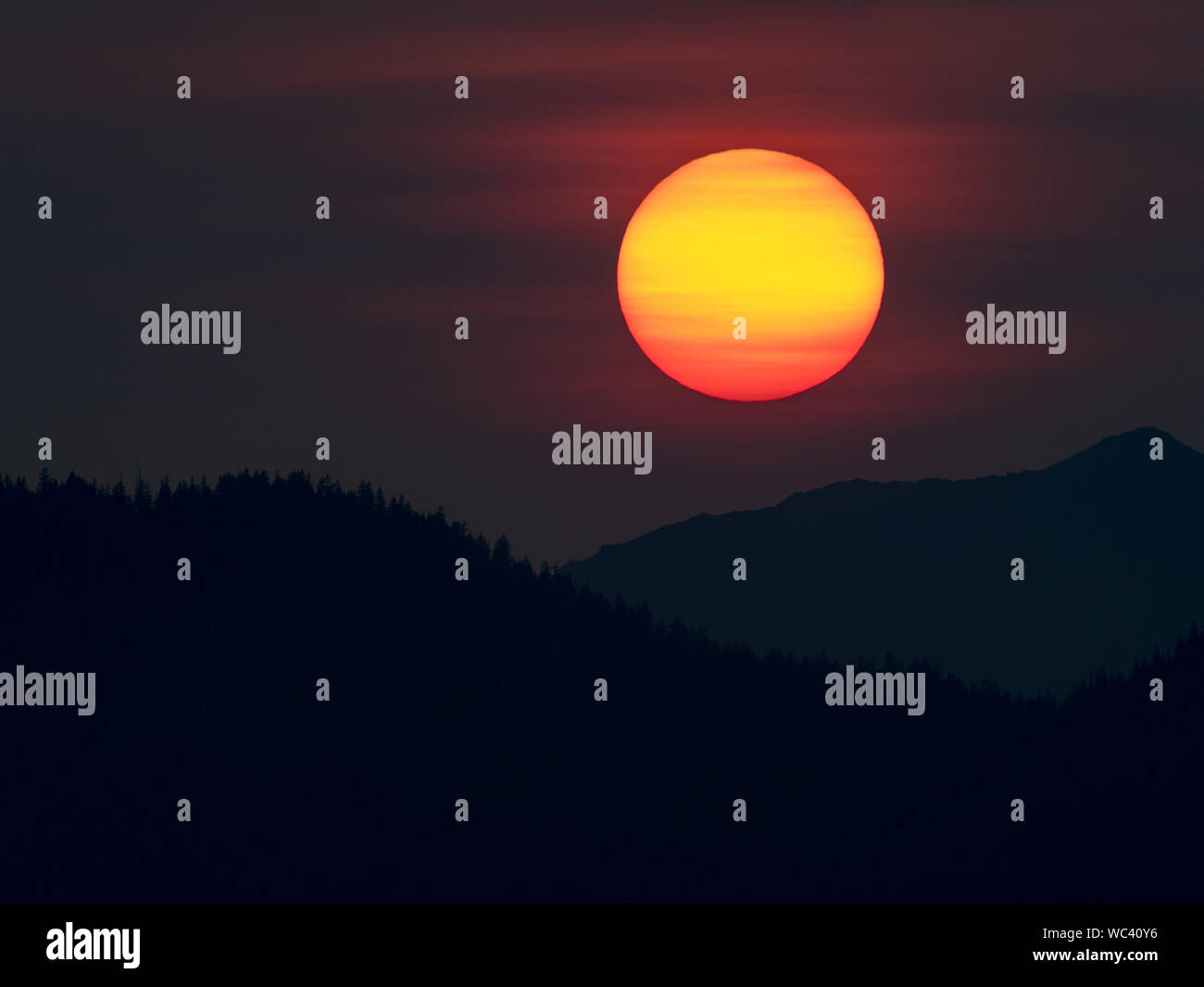 Der Sonnenuntergang über der Insel Chichagof im Südosten Alaskas, USA, machte durch Rauch aus Wildbränden lebendiger Stockfoto