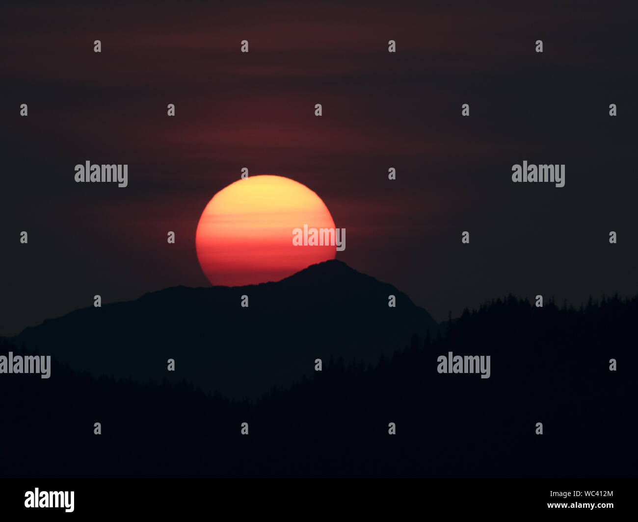 Der Sonnenuntergang über der Insel Chichagof im Südosten Alaskas, USA, machte durch Rauch aus Wildbränden lebendiger Stockfoto