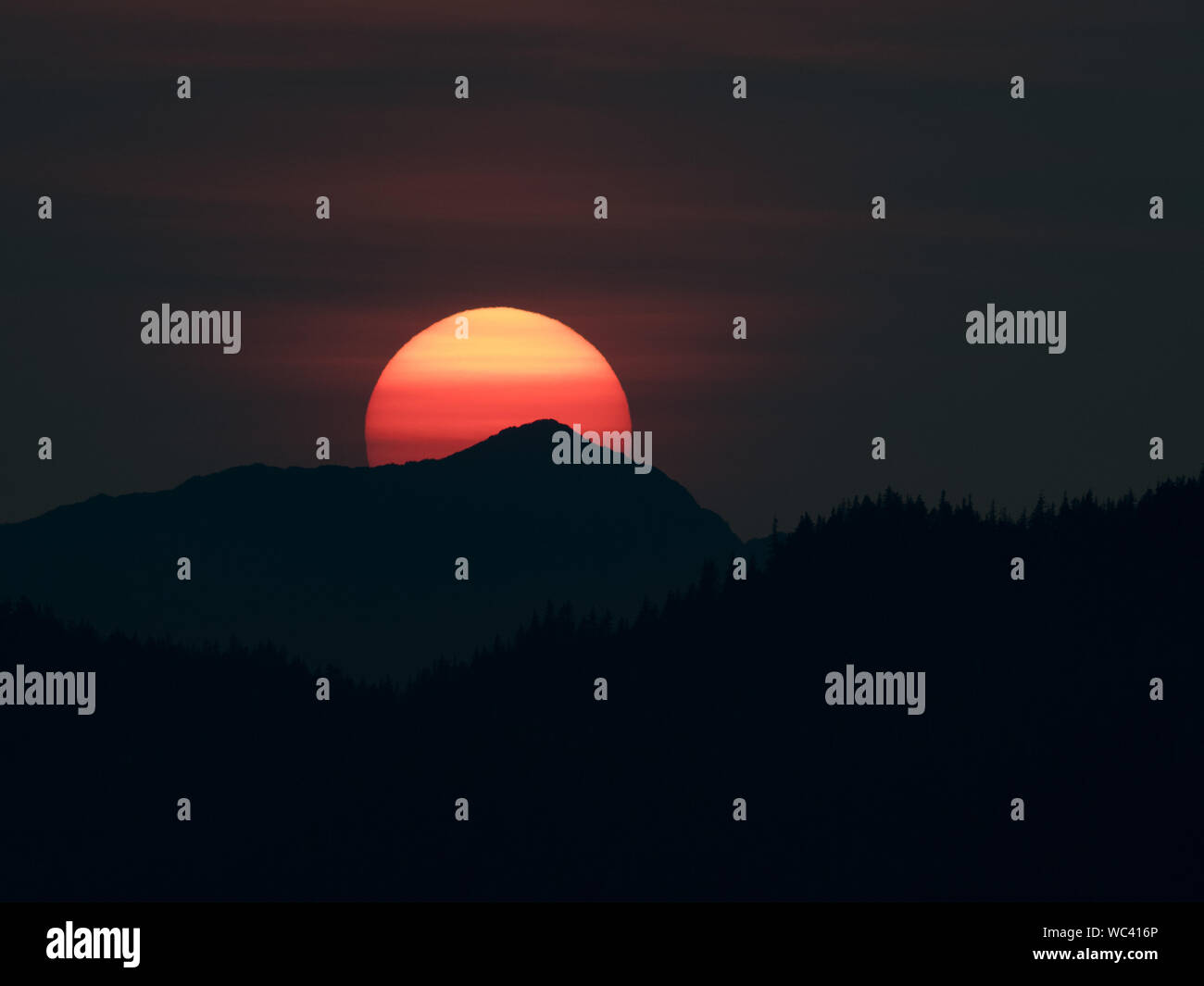 Der Sonnenuntergang über der Insel Chichagof im Südosten Alaskas, USA, machte durch Rauch aus Wildbränden lebendiger Stockfoto
